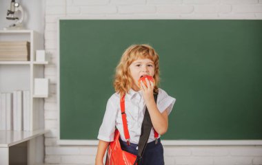 Sınıfta elma yiyen küçük bir öğrenci, okulda İngilizce öğreniyor. Dahi çocuk, bilgi günü