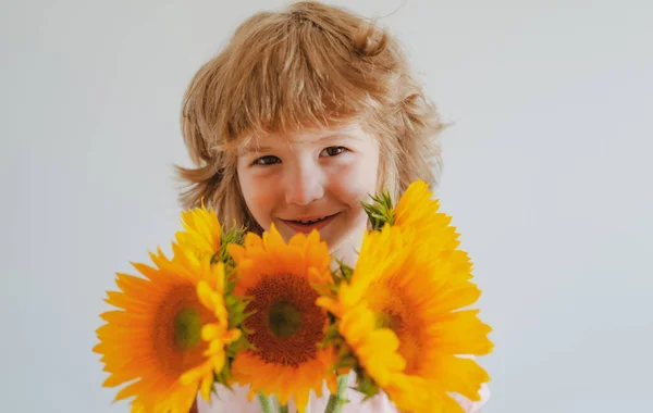Spring child with bouquet of sunflowers. Smiling kid with flowers. Cute lovely boy romantic and surprise