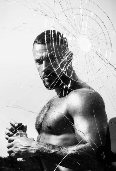 割れ窓ガラスの後ろに香水を提示強い入れ墨の男 本物の機械男のための男性的な香り 男性の力と強さ メンズスタイルとファッションコンセプト — ストック写真