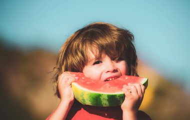 Elinde dilimlenmiş karpuz tutan güzel bir çocuk. Taze tatlı karpuzlar. Çocuklar organik sağlıklı yiyecekler yiyorlar. Sebzeli çocuklar