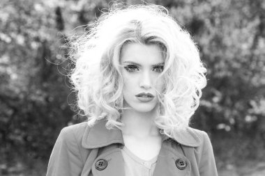 Bahar çiçekleri arka planında şehvetli genç bir kadın. Kıvırcık saçlı, bahar güzeli kız. Bahar makyajı.