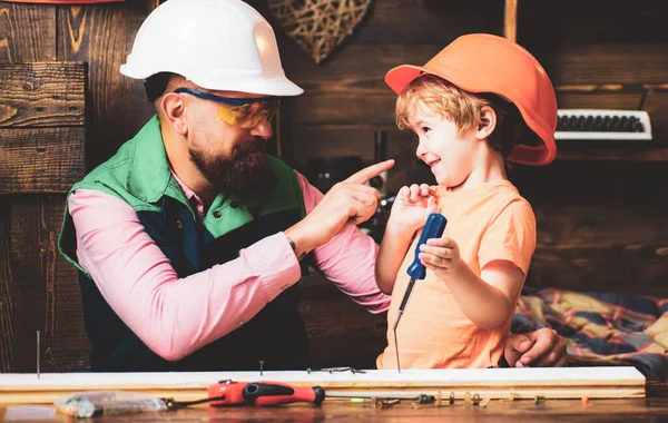 Tools construction. Father teaching little son to use carpenter tools and hammering. Father helping son at workshop