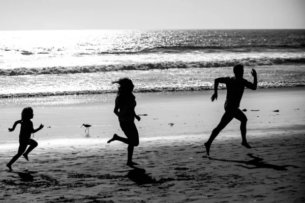 スポーティ家族の父 母親と赤ちゃんの息子が一緒に実行されます 海に沿って水で動く親を持つ子供 夏のスポーツ 健康とフィットネス — ストック写真