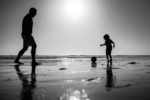 父と息子はビーチでサッカーやサッカーをします 夏の日に子供の男の子とパパ — ストック写真