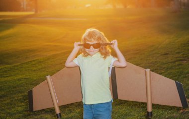 Uçakta uçan pilot gözlüklü çocuk karton kanatlardan yapılmış. Rüya, hayal gücü, çocukluk. Seyahat ve yaz tatili konsepti