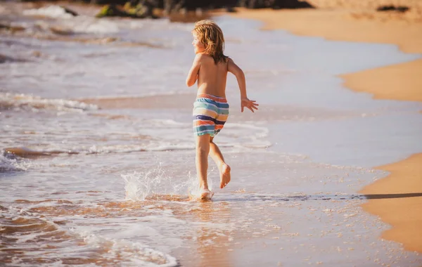 休暇中の夏の日に海の波の中で活発な小さな男の子が飛び散っています 子供と家族の休日の概念 — ストック写真