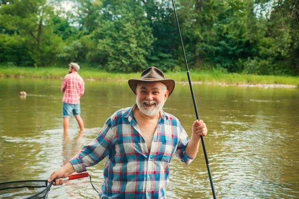 一个快乐的老人钓鱼的画像 祖父和儿子是渔夫 年轻人和老人在河里或湖中钓菠萝 — 图库照片
