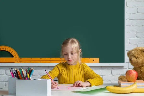 女子高生は教室の黒板の背景を勉強して机に座って授業を学ぶ 子供の概念 — ストック写真