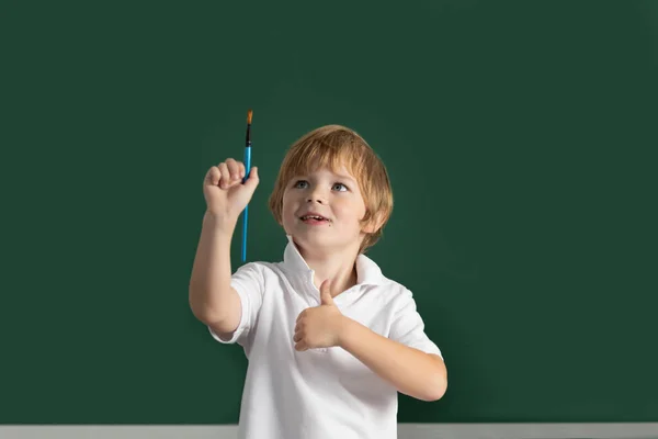 Child boy drawing cute draw using colored pencils at school or kindergarten. Kids creative education concept. Copy space