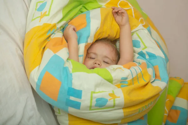 赤ん坊はベッドで寝ている 子供の静かなベッドの上で自宅で寝る 赤ん坊の子供はベッドの上で毛布 健康的な睡眠の下で彼の背中に横たわって寝ている 小さな子供がベッドで一日昼寝をしている — ストック写真
