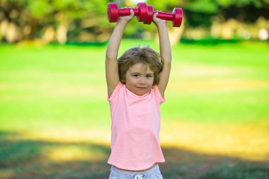 Kol halterli sportif çocuk. Fitness çocukları, sağlık ve enerji. Sağlıklı çocuk yaşam tarzı. Çocuk halterle egzersiz yapıyor. Küçük çocuklar için spor. Spor portresi çocuklar.