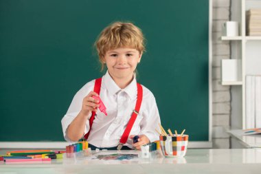 Boyama kalemleriyle resim yapan çocuk, erken gelişim resimleriyle resim yapan çocuk. Resim dersi alan çocuk resim ödevi yapıyor. Çocuk ilkokulda resim çiziyor.