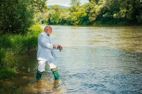 身穿西服的资深富商渔夫钓到了一条鱼 在河里钓鱼的人 — 图库照片