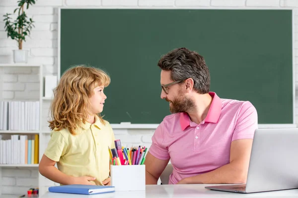 Pupil kid student and teacher tutor in classroom at school lesson. Pupil of primary elementary school has lesson. Kid boy with teacher learn english language or mathematics