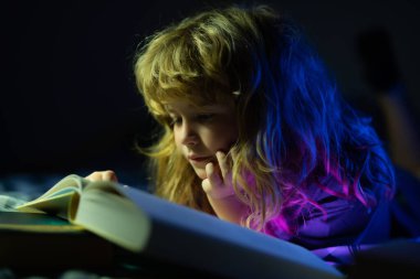 Küçük bir çocuk karanlık evde kitap okuyor. Çocukların yüzü gece lambasıyla kaplıdır. Yatmadan önce masal masalı