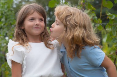 Küçük oğlan ve utangaç kız aşık. Neşeli çocuklar dışarıda parkta oynuyorlar. Mutlu şirin çocukların yaz portresi. Sevimli çocuk, ilk çocuklar bayılır. Çocuklar dışarıda beraber oynuyorlar.