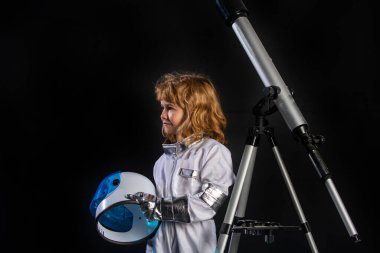Uzay kaskı, metal giysisi ve teleskopu olan bir astronot olmak için oynayan çocuk. Başarı, yaratıcılık ve başlangıç konsepti