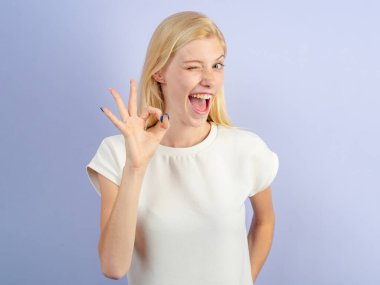 Gülen kadın iyi niyet gösteriyor. Beyaz arka planda izole edilmiş bir kadın parmaklarıyla işaret gösteriyor. Kadın duygularını gösteren komik bir genç kız. Duygusal yüz.