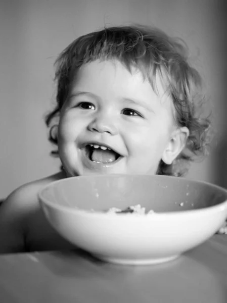 厨房里有趣的小宝宝用手指从盘子里吃东西 开心的孩子面对特写镜头 — 图库照片