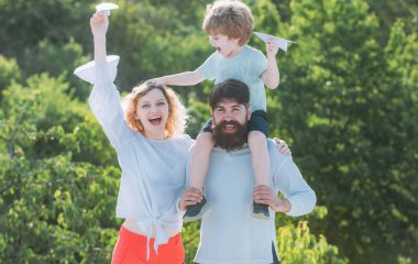 Mutlu aile ve küçük oğlu mavi gökyüzünde oynuyorlar. Baba, anne ve oğul parkta. Mutlu aile gülümsemesi ve kucaklaşması. Baba, anne ve bebek dışarıda birlikte oynuyorlar.