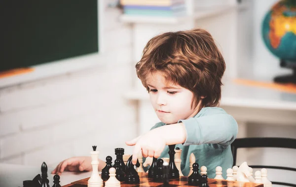 Pupil kid thinking about his next move in a game of chess. Concentrated  little boy sitting at the table and playing chess Stock Photo - Alamy