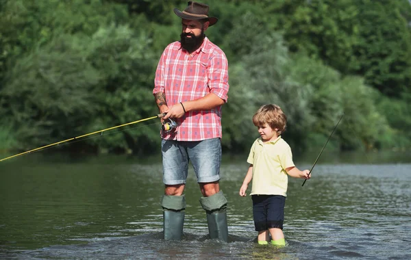 Father and son fishing and relaxing while enjoying hobby. Anglers. Fishermen father and son fishing in a river with a fishing rod