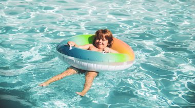 Havuzdaki çocuk, rahatla şişme yüzükte yüz ve yaz tatilinde suda eğlen.