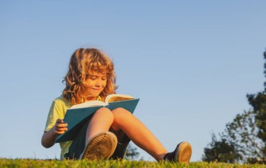 Akıllı çocuk parkta kitap okuyor.