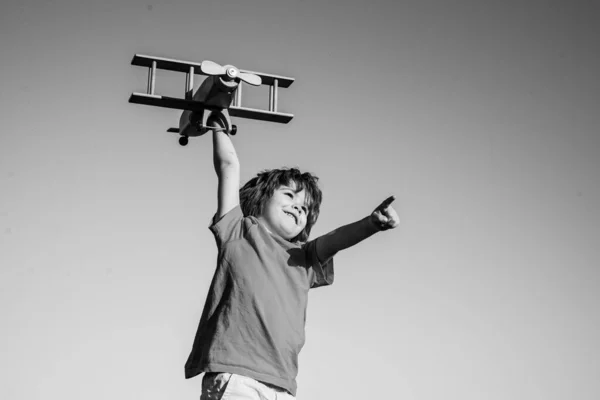 夏の空を背景にしたおもちゃの木製飛行機で遊ぶ幸せな子供 — ストック写真