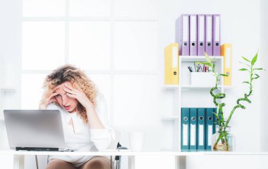 Masasında dizüstü bilgisayarı olan yorgun ve uykulu bir iş kadını. Yorgun ofis çalışanı