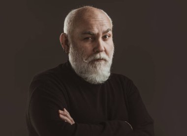 Yaşlı, yaşlı, olgun bir adam kıdemli adamın portresini yakından çekiyor. Siyah arka planda olgun bir adamın portresi