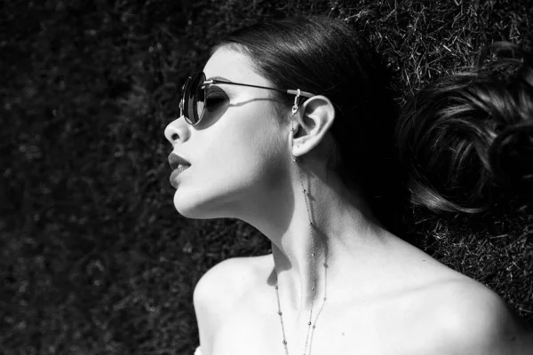 Güzel genç bir kadın çimlerin üzerinde yatıyor. Taze doğal bahar konsepti. Temiz ciltli güzel bir genç kadın. Yüz bakımı. Kozmetik, güzellik ve kaplıca. Çimlere uzanmış şehvetli kız