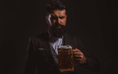 Bira içen ciddi sakallı bir adamın portresi. Bira bardağı tutan mutlu bira üreticisi