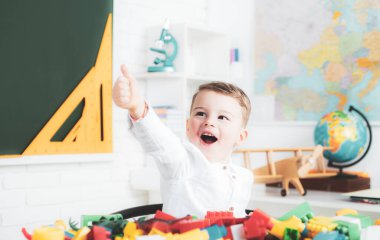 Gözlüklü komik çocuk tahtayı işaret ediyor..