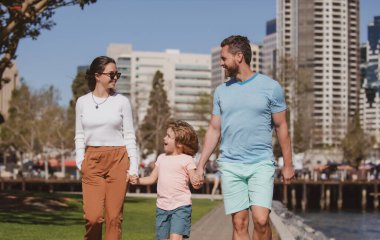 Şehirde çocuğuyla yürüyen mutlu genç bir ailenin portresi. Halk kentsel konsepti