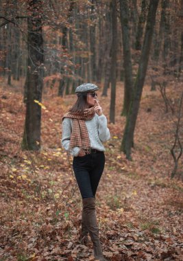 Rahatlatıcı sigara. Kadınlar yalnız sigara içmekten hoşlanır. Sonbahar melankolisi. Sonbahar geldi. Şapkalı, güneş gözlüklü, sigara içen güzel bir kadın. Sonbahar moda aksesuarı. Sonbaharın tadını çıkar.