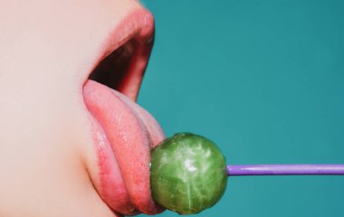 Parmak izi için şekerli, şehvetli kırmızı dudaklar. Sanat tasarımında ağzında kırmızı lolipop var. Parlak kadın dudakları lolipop yalıyor. Şehvetli seksi ağız ve şeker kavramı. Güzel kadın dudakları.