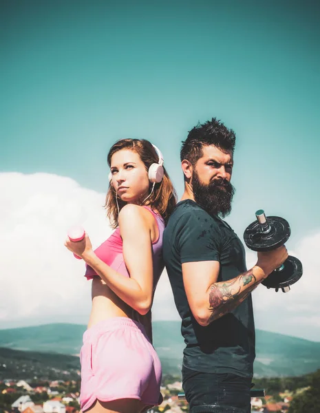 Active lifestyle concept. Beautiful slim sexy woman with good body forms wearing hot pink sportswear and doing sport fitness exercises with her handsome bearded coach