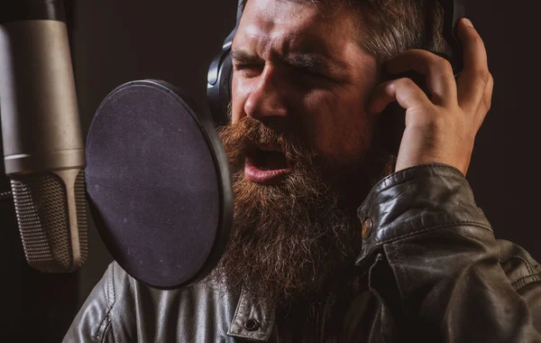 Singing man in a recording studio. Expressive face closeup