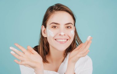 Kadın yüzü, güzel bir kadın modelin portresi. Güzellik kızı, nemlendirilmiş yumuşak cilde, besleyici krem sürerek yüz kremi sürüyor. Cilt bakımı, cilt bakımı, yüz bakımı.