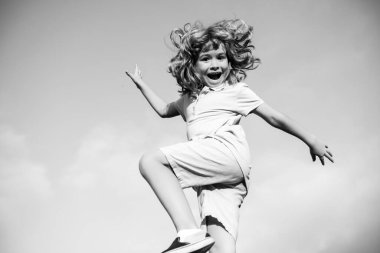 Mavi gökyüzündeki parkta eğlenen komik, mutlu küçük çocuk. Çocuk doğanın tadını çıkarıyor, çocukluk kavramı