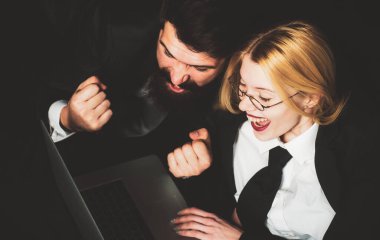 Çift, onun defterindeki online spor kumar uygulamasında bahsi kazanmaktan mutlu. Bilgisayarı siyah arka planda olan heyecanlı iş adamları izole edildi. Genç çift dizüstü bilgisayarda çalışıyor ve gülümsüyor.