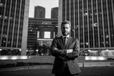 Ofisin dışında duran kendinden emin bir iş adamının portresi. İş yerinin dışında kolları kavuşturulmuş gülümseyen iş adamı CEO 'su. İyi giyimli iş adamı.