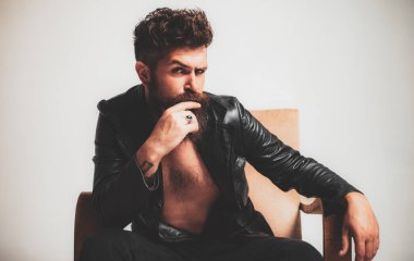Seksi bir adam. Gece kulübünde şık bir modacı. Kendine güveni tam, odaklanmış, modern ceketli yakışıklı sakallı adam kanepeye oturur. Saygıdeğer erkeklerin güzelliği, modası. Genç hippi.
