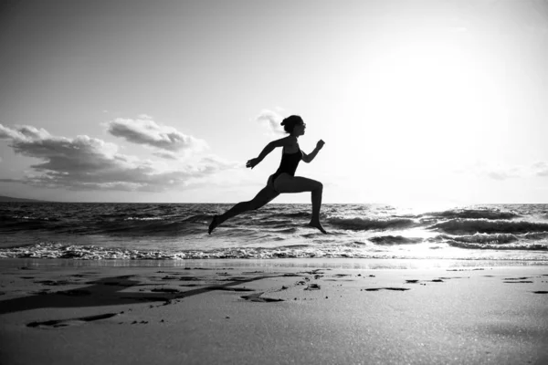 在海滩上奔跑的女人穿着运动服在海上跑步的漂亮姑娘 — 图库照片