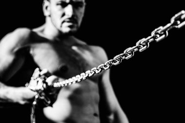 Siyah arka planda zincirli kaslı bir adam.