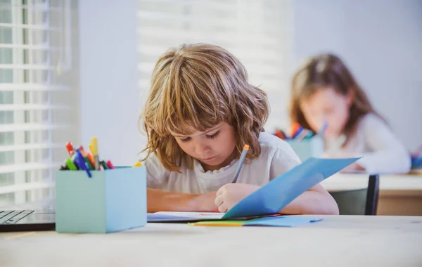 学校的孩子在抄袭本上写东西 坐在教室的桌旁 抄本中儿童绘画的肖像 — 图库照片