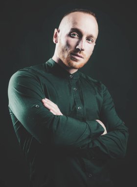 Çapraz kollu ciddi bir adam içeride poz veriyor. Moda erkek modeli.