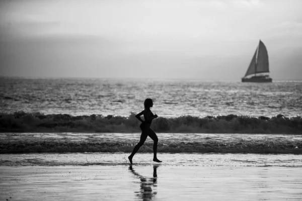 サンセット時にビーチで走るランナー女 — ストック写真
