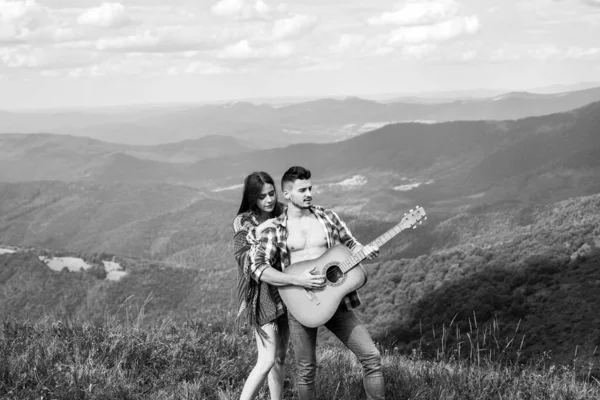 ハンサムなヒップスターの男性と女性はギターで山の中に残ります 背景に渓谷の美しい景色 — ストック写真